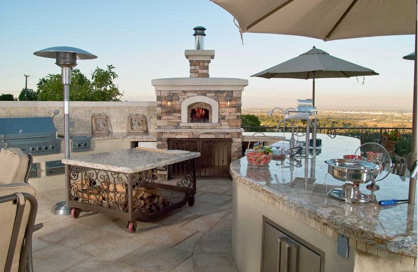 Outdoor Kitchen with a Large Stone Fireplace and Granite Countertops