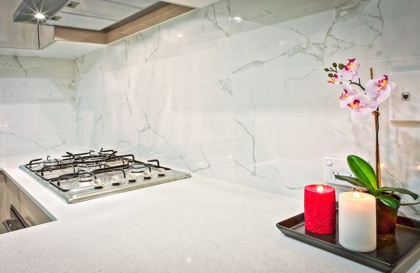 Two lit candles and a flower in front of a modern marble backsplash