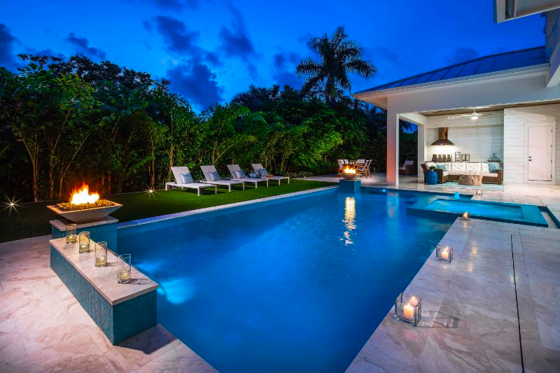 Luxury outdoor patio with pool, candle lights, and fire pits