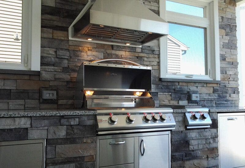 Outdoor hood over grill with stone backsplash