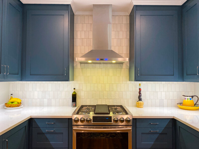 Blue gray cabinets with vent hood over stove