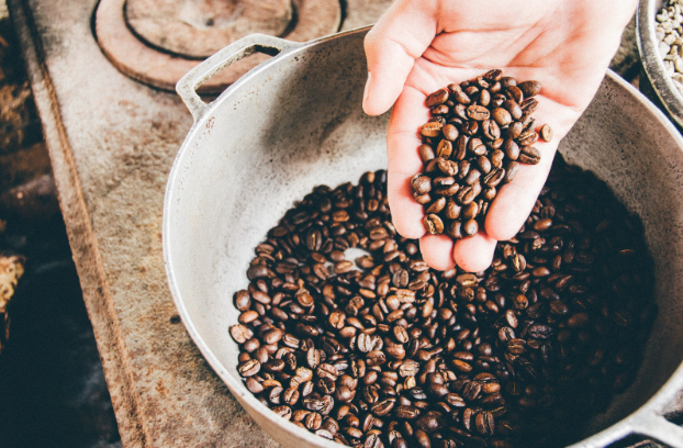 Person pouring coffee beans into a rustic bowl