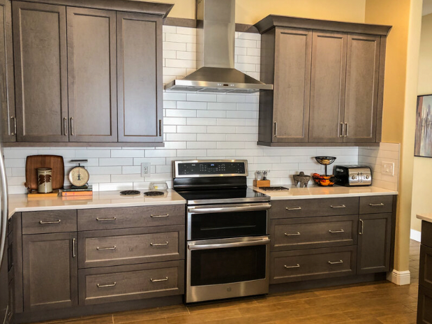 upper and lower brown cabinetry in kitchen with vent hood over electric stove