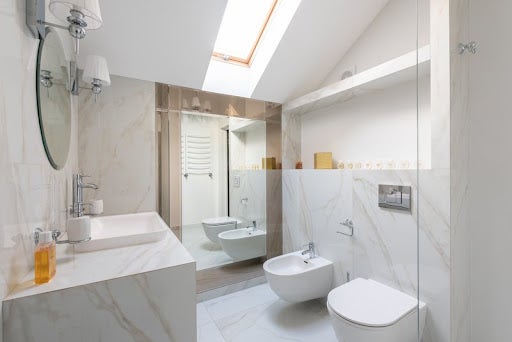 Marble bathroom with a toilet, bidet, and sink