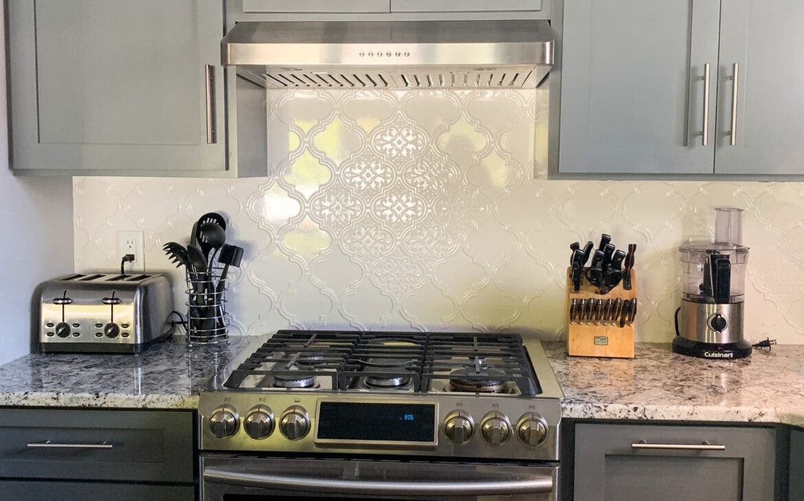 PLJW 185 - Quietest Range Hood. Featuring a unique backsplash, grey cabinets, and marble countertops. 