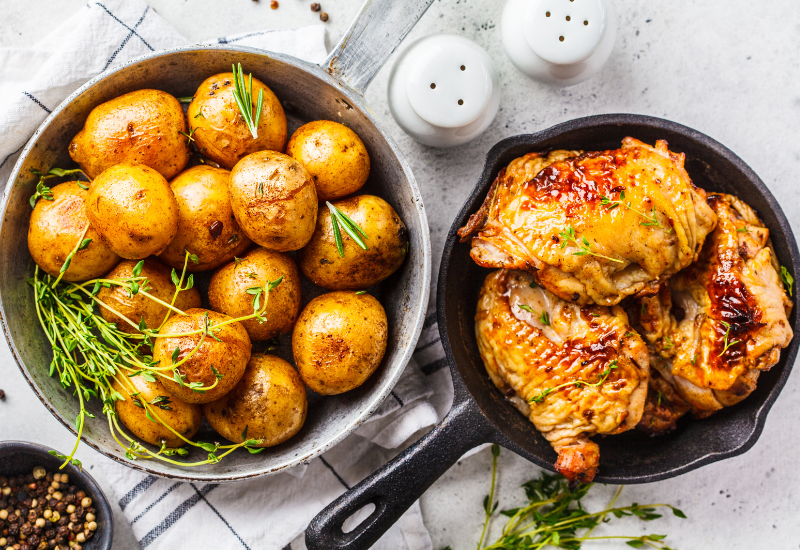 A mouth-watering Cornish game hen is sizzling in a seasoned cast iron pot, while a bowl of whole baked potatoes sits nearby, ready to be enjoyed. The rustic and earthy feel of the seasoned cast iron adds to the overall experience of enjoying a wholesome and hearty meal. Salt and pepper shakers are within reach, allowing for the perfect seasoning of the meal to suit individual tastes. A variety of other seasonings are also available on the table, providing endless possibilities for flavor combinations. The combination of the seasoned cast iron and the delicious meal creates a warm and inviting atmosphere that is perfect for any dining occasion.