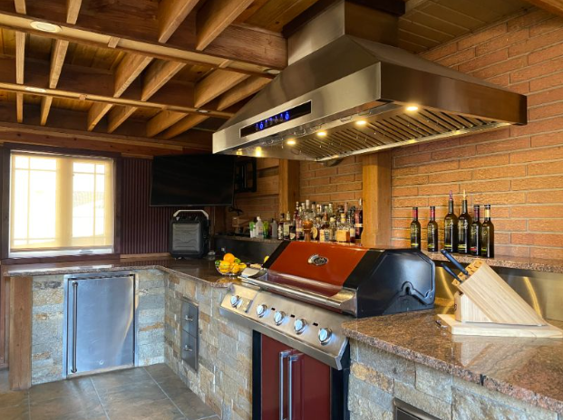 outdoor kitchen idea number 5
stainless steel appliances with a big range hood over a grill and lots of dressings and knives and stone all around