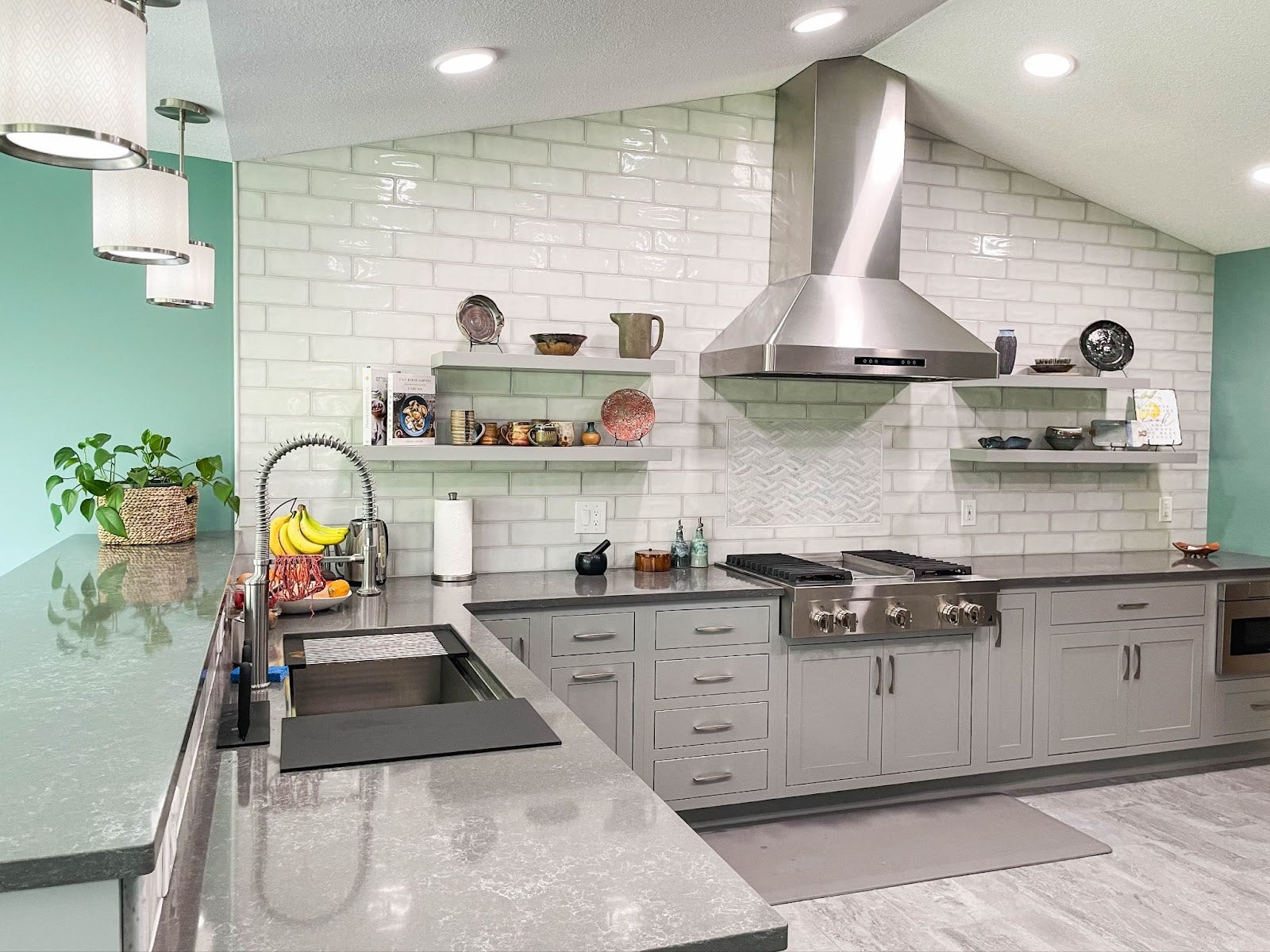 Kitchen with stainless steel appliances and open shelving. - Proline Range Hoods - prolinerangehoods.com 