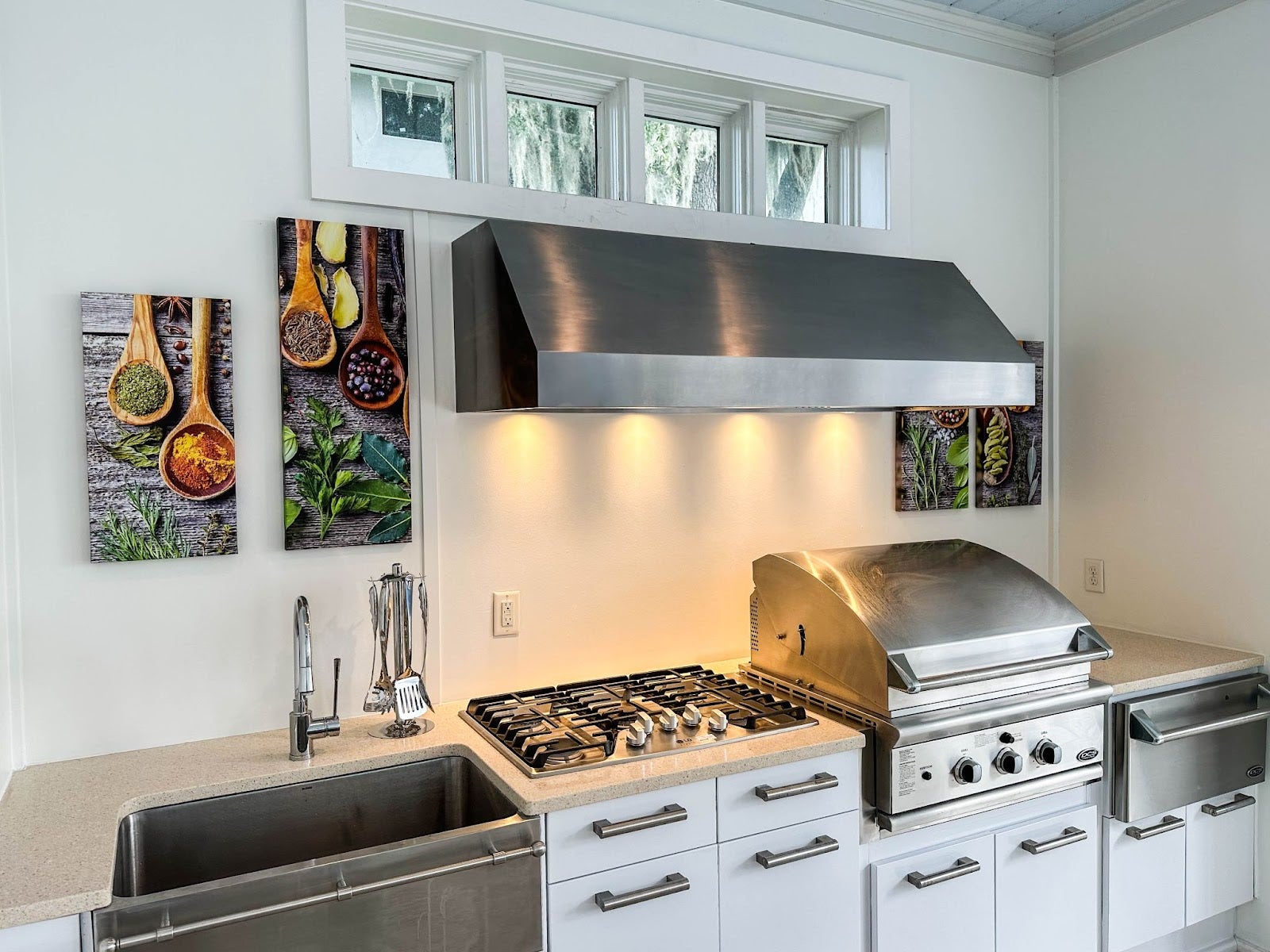 Stainless steel appliances, white cabinets, and a Proline range hood in a modern kitchen. - Proline Range Hoods - prolinerangehoods.com 