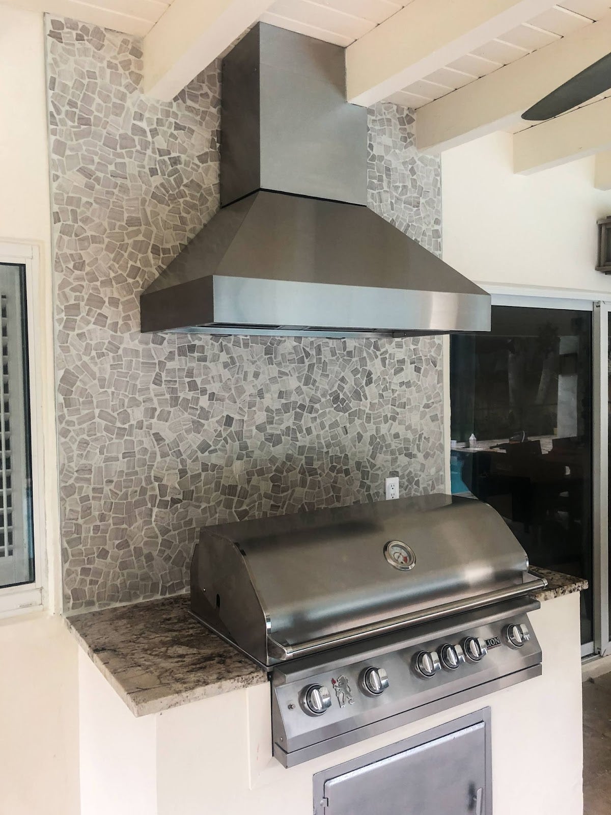 Fresh & Airy BBQ Area: Proline hood keeps smoke at bay in this bright outdoor kitchen. Mosaic backsplash and granite countertops add a touch of style. Perfect for sunny BBQ days! - Proline Range Hoods - prolinerangehoods.com 