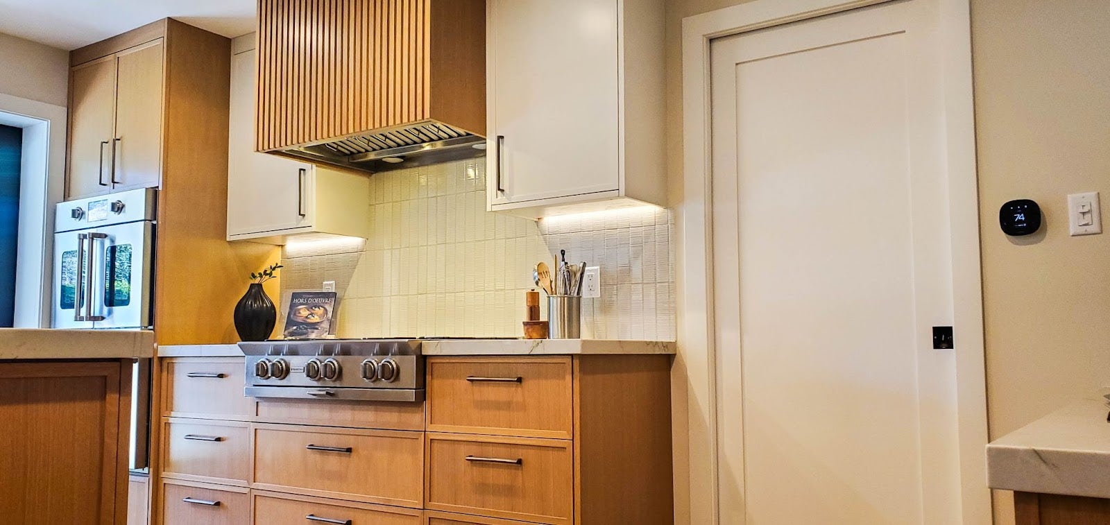 Modern kitchen featuring Proline range hood, white cabinets, and marble countertops. - Proline Range Hoods - prolinerangehoods.com 