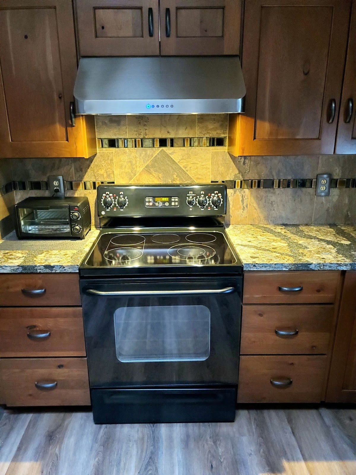 Modern kitchen with Proline range hood, white cabinets, and black granite countertops. - Proline Range Hoods - prolinerangehoods.com 