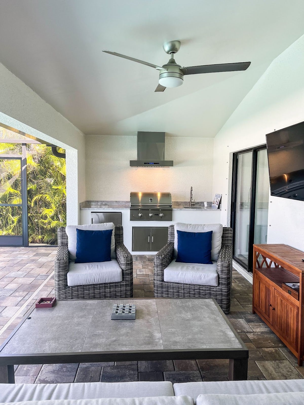 Relaxed Patio for Entertaining: Comfy seating and screened area create a cozy vibe in this outdoor patio. Modern Proline hood vent complements the stainless steel grill for a stylish touch. Perfect for enjoying long summer evenings with friends - Proline Range Hoods - prolinerangehoods.com 