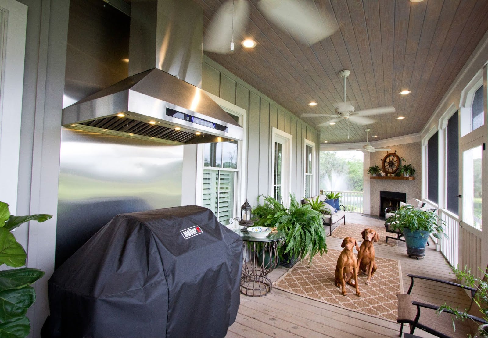 Southern Charm Outdoor Kitchen: Proline PLJI 102 hood vents smoke in this inviting outdoor kitchen. Fireplace and comfy porch seating create a relaxing space for grilling and socializing. - Proline Range Hoods - prolinerangehoods.com 