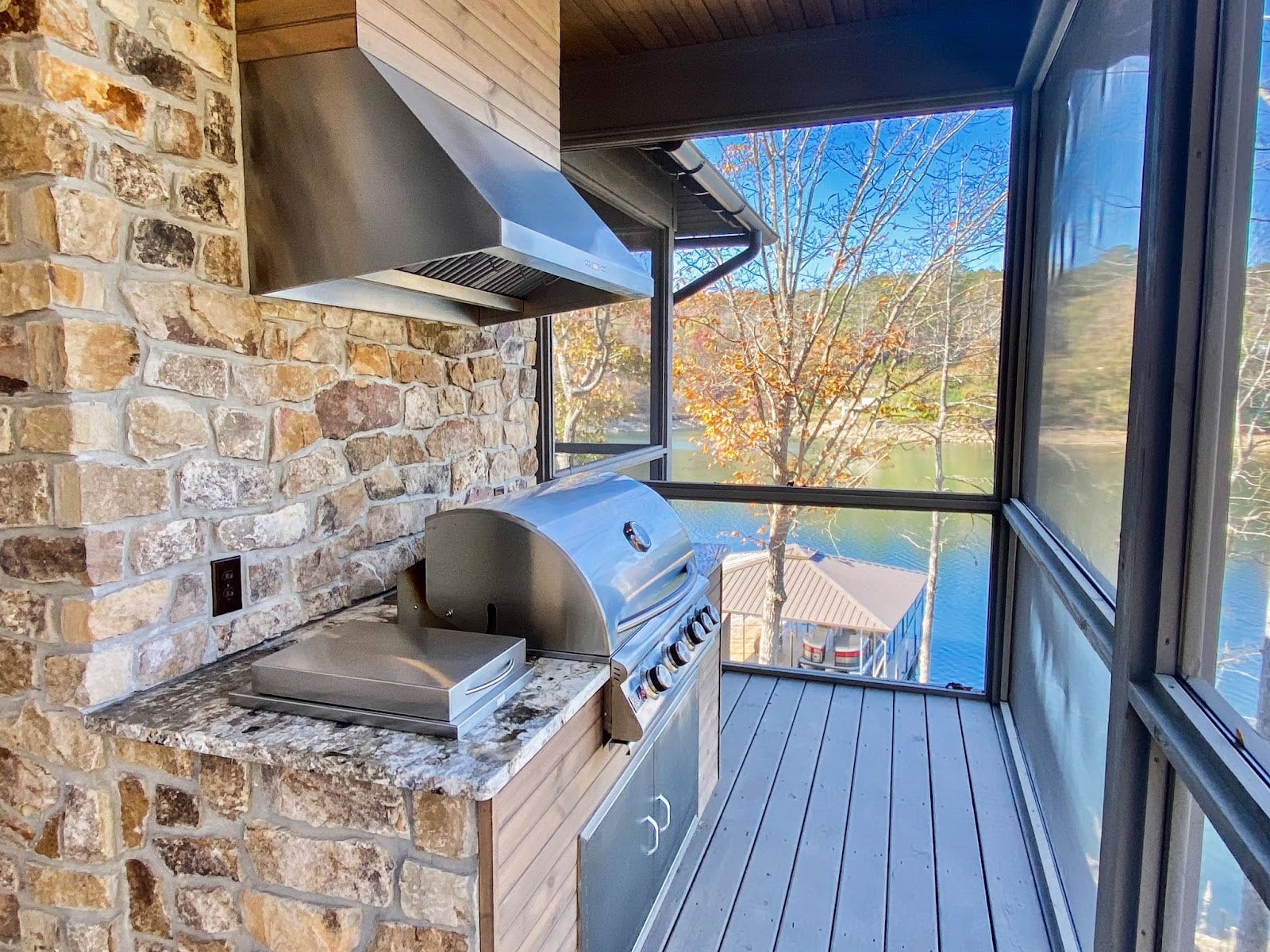 Lakeview Screened Kitchen: Modern screened porch with Proline hood and grill for scenic lakefront cooking. Stone wall and granite countertops create a luxurious feel.  - Proline Range Hoods - prolinerangehoods.com  