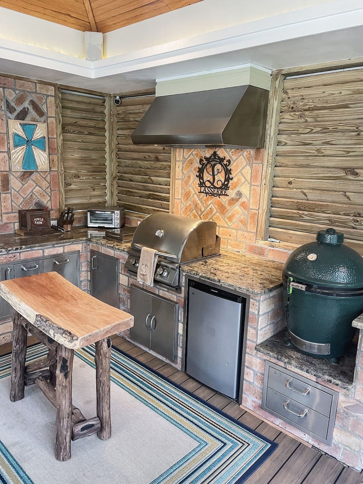 Rustic Comfort Meets Modern Function: Proline PLJW 109 hood keeps the air clear in this cozy outdoor kitchen. Warm brick and natural wood create a charming space for grilling and entertaining, perfect for family meals or social gatherings. - Proline Range Hoods - prolinerangehoods.com 