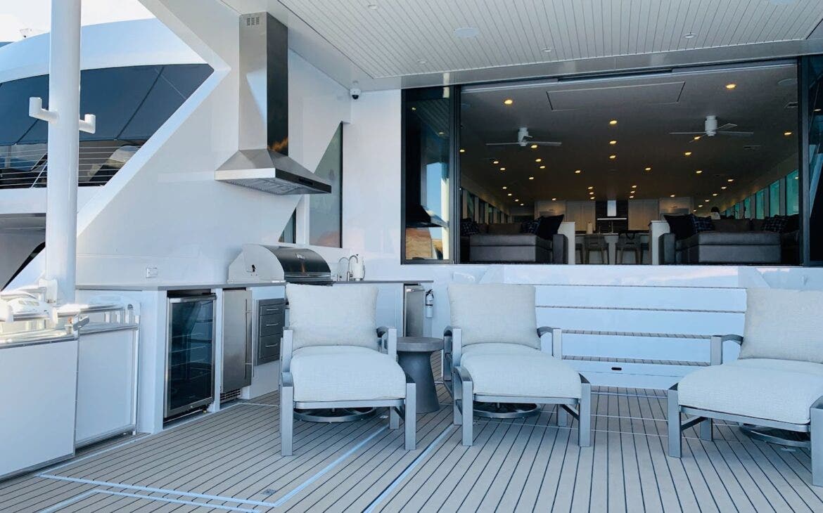 Yacht Outdoor Kitchen: Sleek Proline hood vents smoke on this modern yacht. Stainless steel and white furniture create a sophisticated entertaining space with a sea view. - Proline Range Hoods - prolinerangehoods.com 