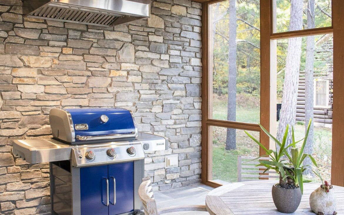 Rustic Forest Kitchen: Proline hood keeps the air clear for grilling in this outdoor kitchen. Stonework and open woods create a natural setting. Perfect for enjoying the outdoors and smoky flavors. - Proline Range Hoods - prolinerangehoods.com 