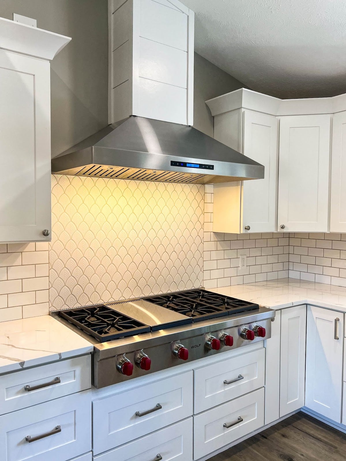 White cabinets and a stainless steel stove in a clean kitchen. - Proline Range Hoods - prolinerangehoods.com 