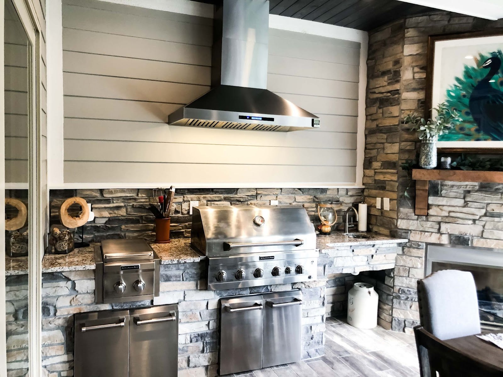 Stylish outdoor cooking area featuring a Proline range hood, stone fireplace, and premium grilling equipment - prolinerangehoods.com