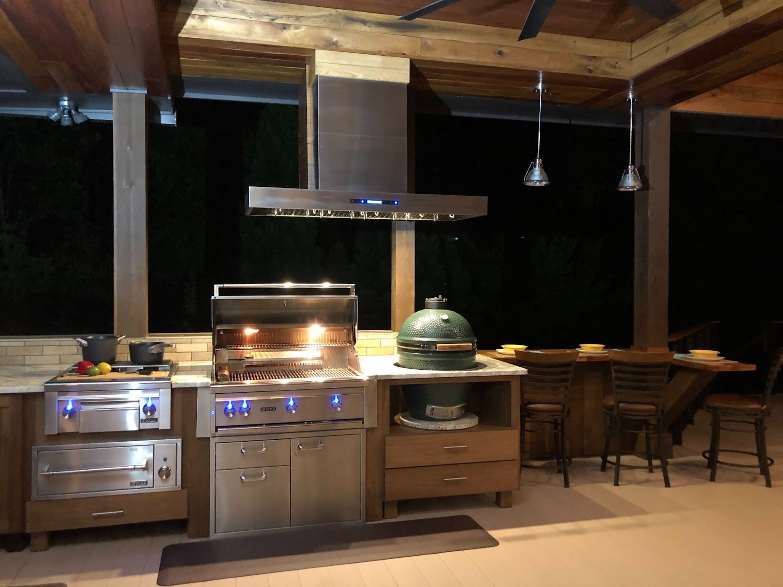 Proline range hood illuminating a cozy outdoor kitchen at night - prolinerangehoods.com