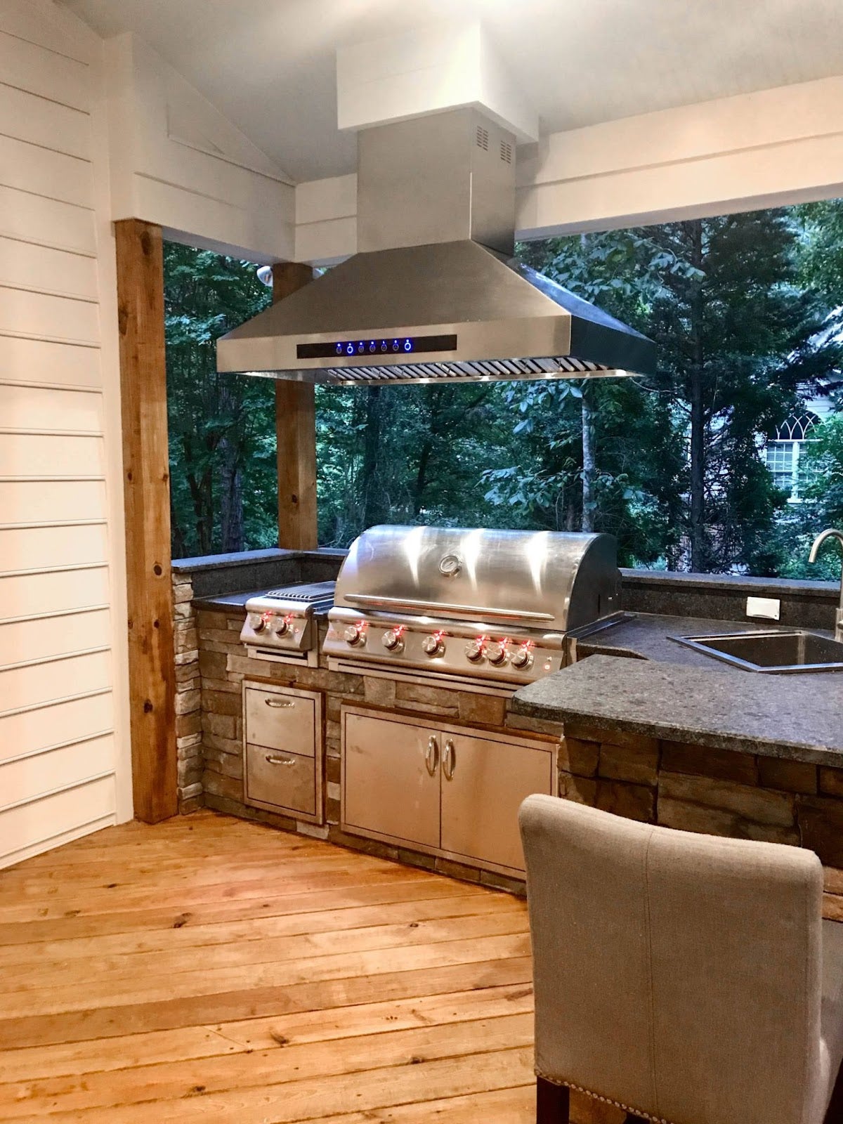 Serene outdoor kitchen setup with a stainless steel Proline range hood and rustic wooden and stone design - prolinerangehoods.com