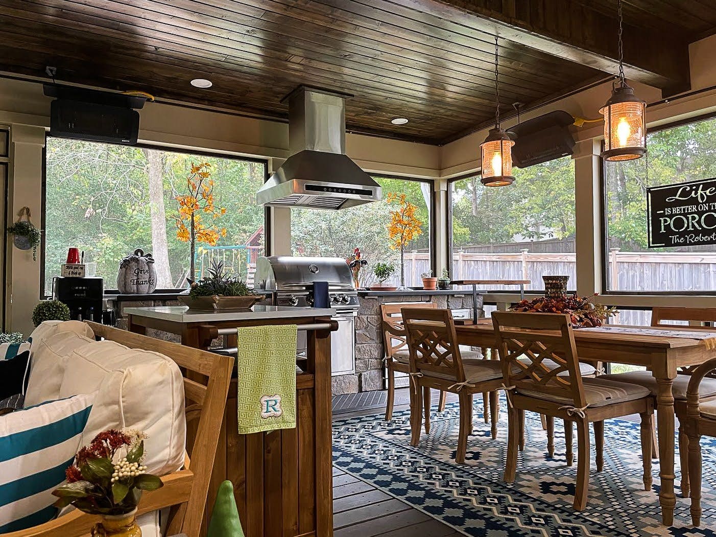 Rustic screened-in porch with a Proline range hood, stylish dining set, and decorative fall touches - prolinerangehoods.com