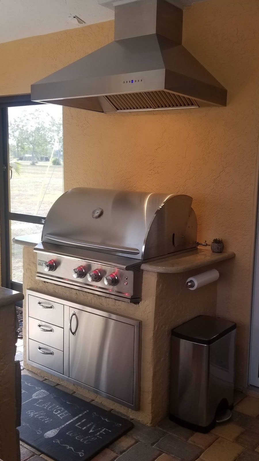 Proline range hood towering over a premium outdoor grill with a stone countertop and ample cabinet storage, creating a perfect backyard cooking spot - prolinerangehoods.com.