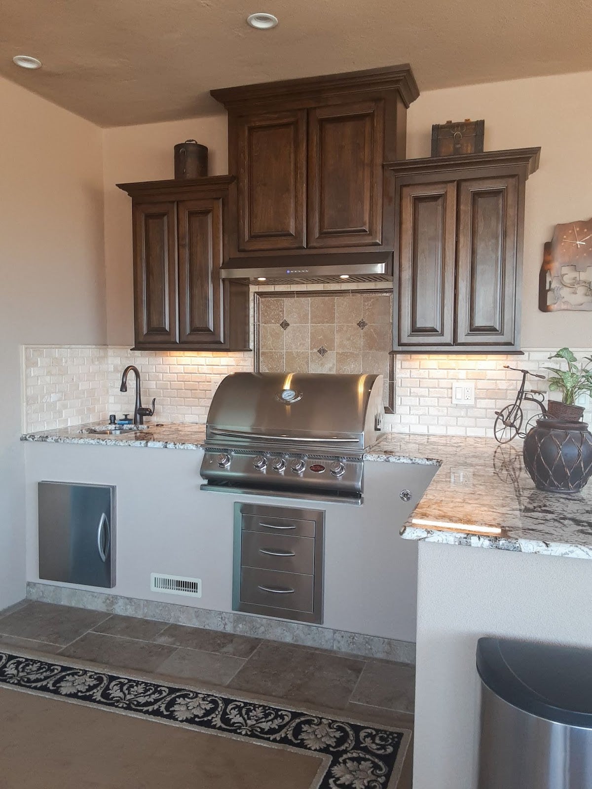 Traditional kitchen design with a Proline range hood complementing dark wood cabinets, beige tile backsplash, and a built-in stainless steel grill - prolinerangehoods.com.