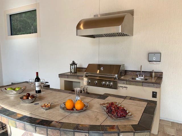 Gourmet outdoor kitchen setup with a Proline range hood, stainless steel grill, and stone countertops, ready for entertaining with fresh ingredients and wine - prolinerangehoods.com.
