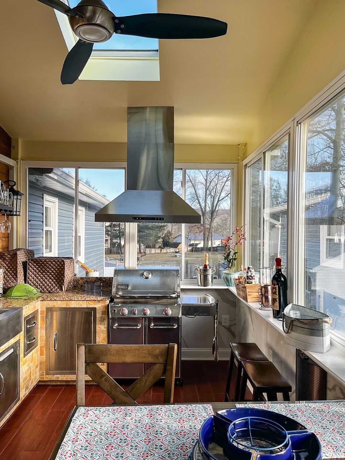 Bright and homey kitchen nook featuring an indoor grilling station with a view of the neighborhood through surrounding windows.