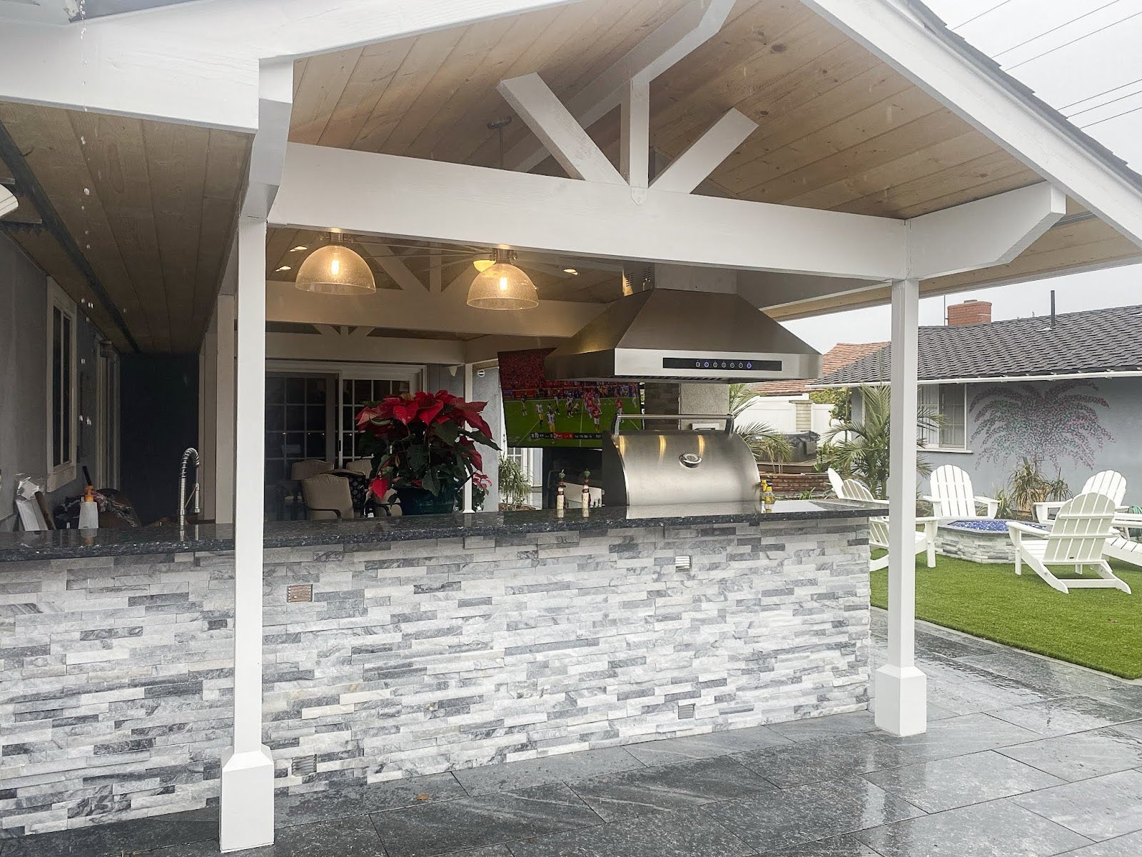 Open-air kitchen with Proline range hood, stone wall detailing, and comfortable outdoor seating - prolinerangehoods.com