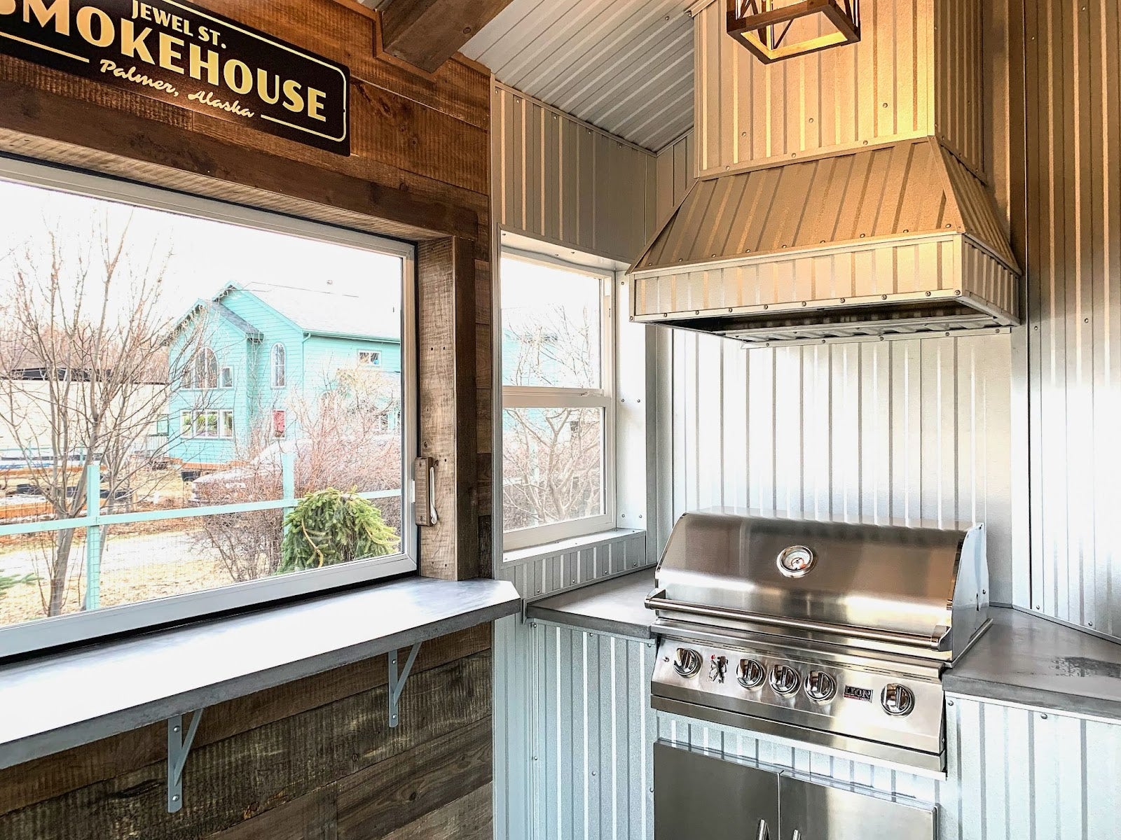 Rustic metal-clad outdoor kitchen with a Proline range hood, providing a unique culinary experience with a view - prolinerangehoods.com