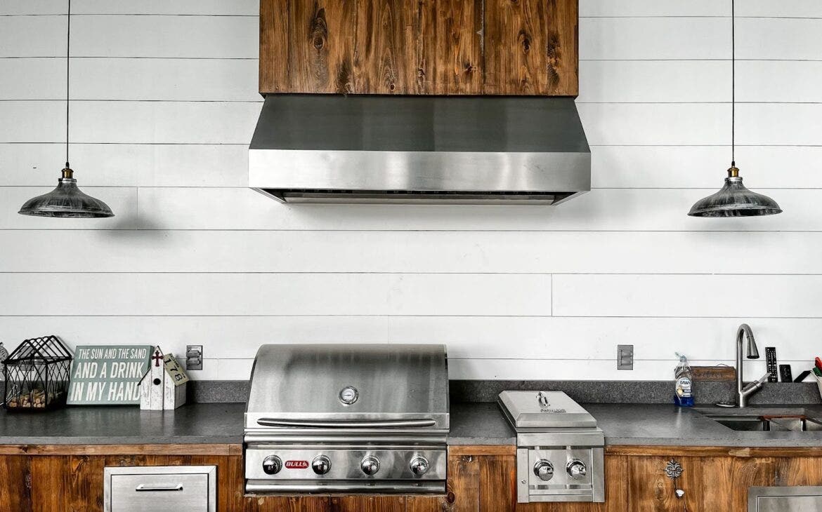 Versatile Proline outdoor range hood seamlessly integrated into a custom outdoor kitchen with a stainless steel grill, enhancing outdoor cooking experiences - learn more at prolinerangehoods.com.