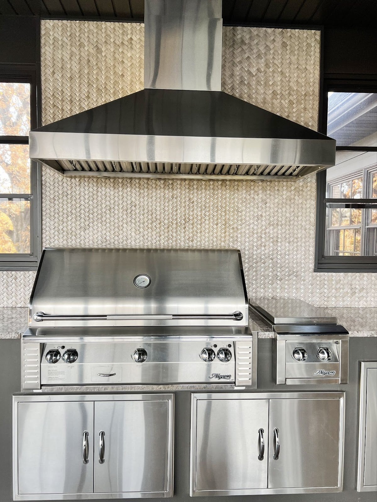Sophisticated outdoor grilling setup featuring a Proline range hood, premium stainless steel grill, and cabinets with textured backdrop - prolinerangehoods.com.