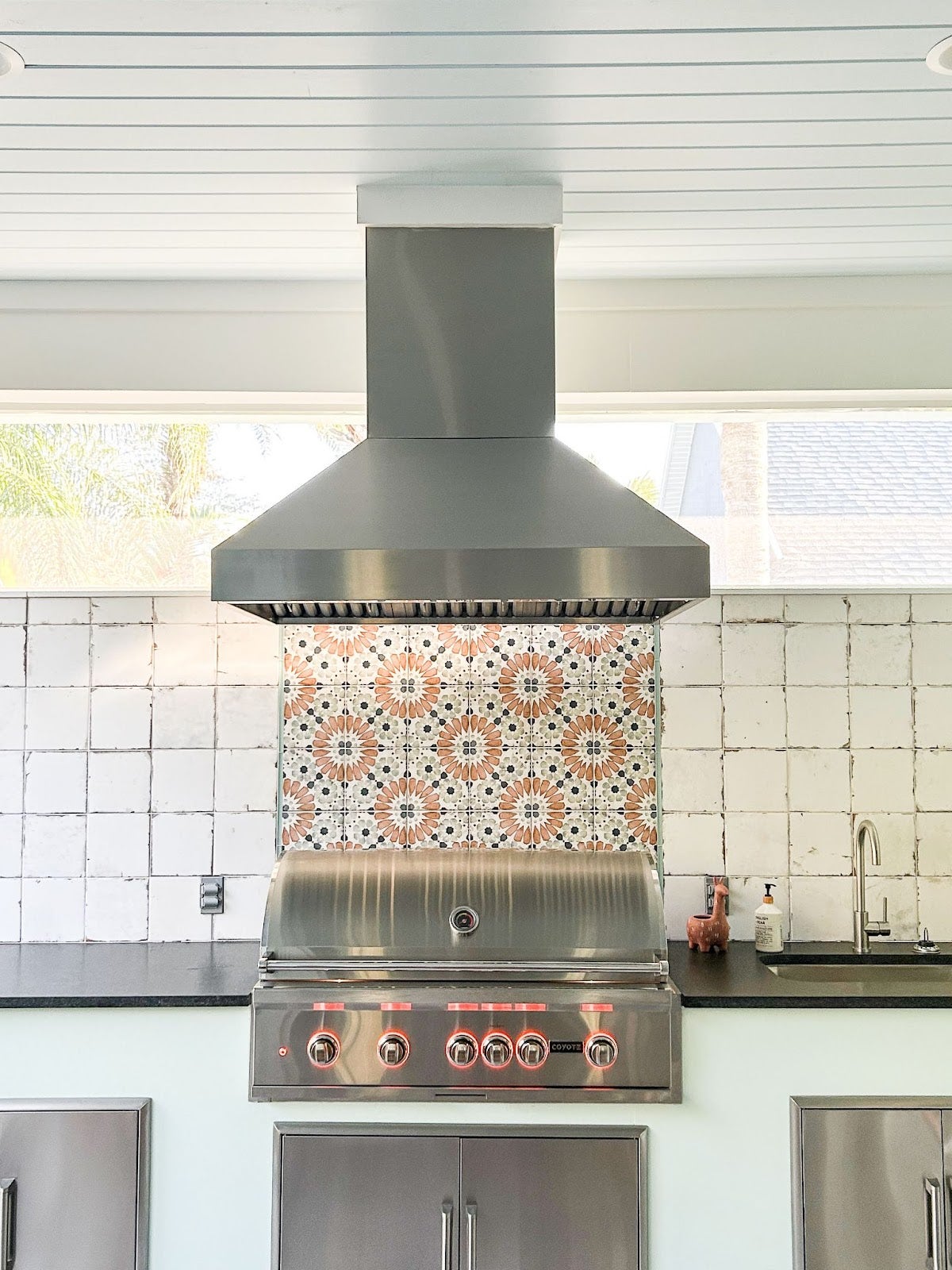 Vibrant outdoor kitchen featuring a Proline range hood, with a decorative tile backsplash and a stainless steel grill, providing a festive cooking experience - prolinerangehoods.com.